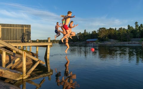 Ungdomar hoppar från bryggan i vattnet